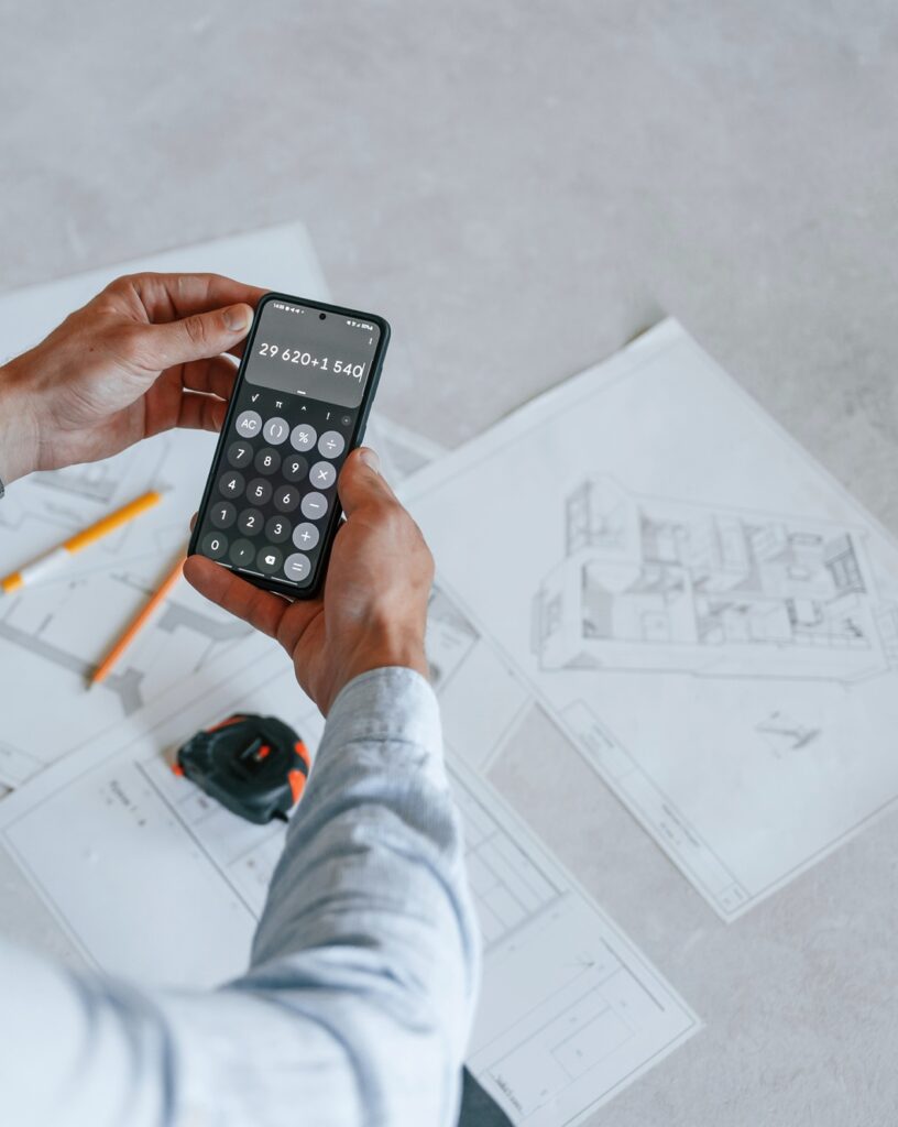 Calculating numbers by using smartphone. The man is making repairs in the apartment