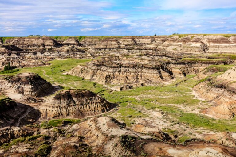 Scenic shot of a valley in Drumheller with a layer of green grass on the eroded surface